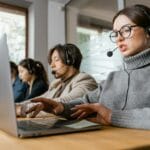 Polityka społeczna w praktyce: jak programy świadczeń wpływają na rynek pracy Pracownicy call center przy laptopach w nowoczesnym biurze