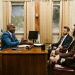 Pełnomocnictwo w sądzie: kiedy warto mieć adwokata? Adwokat rozmawia z klientem w kancelarii podczas spotkania biznesowego