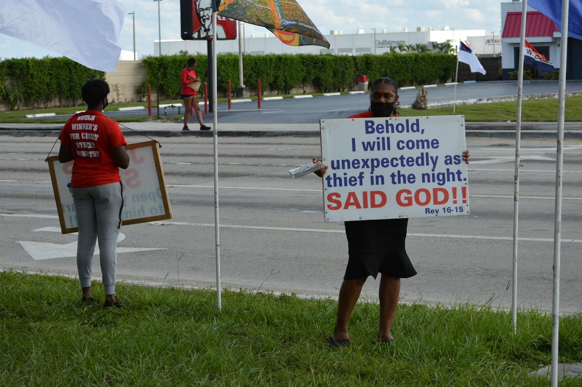 Dwie osoby na ulicy dyskutują, trzymając religijne plakaty