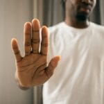 Odmowa składania zeznań: komu przysługuje i jakie ma skutki procesowe? Mężczyzna w pomieszczeniu pokazuje dłonią gest odmowy zeznań