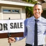 Agent nieruchomości z tablicą na sprzedaż przed domem po spadku