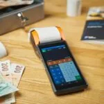 Terminal płatniczy na biurku z gotówką i paragonami