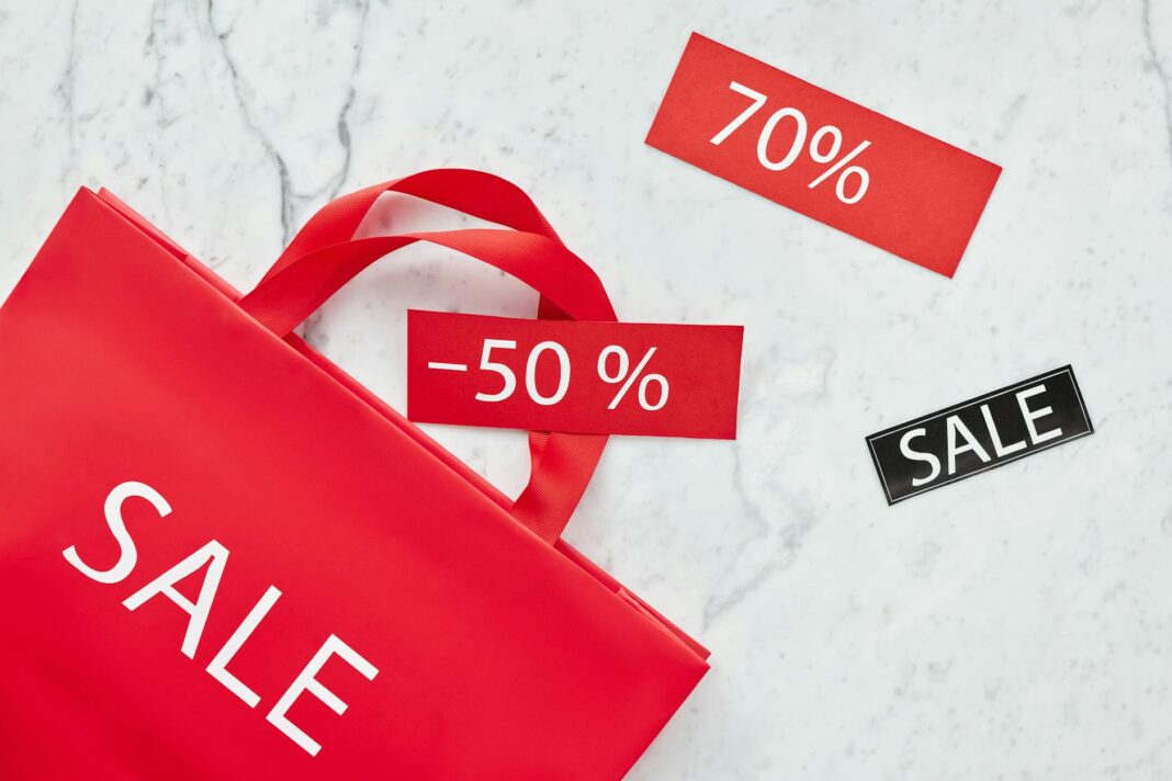 Czerwona torba z napisem sale i metkami rabatów 50% i 70% na tle marmuru