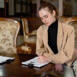 Młoda kobieta podpisuje dokumenty u notariusza w nowoczesnym biurze