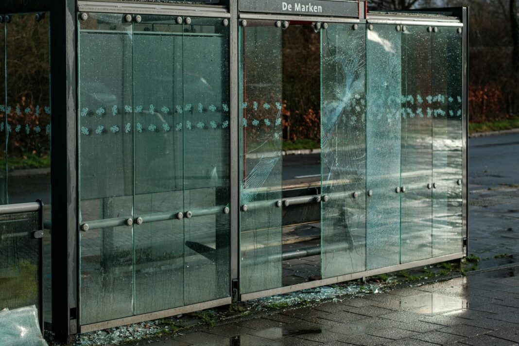 Zniszczona szklana wiata przystankowa na deszczowej ulicy miejskiej