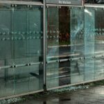 Zniszczona szklana wiata przystankowa na deszczowej ulicy miejskiej