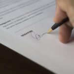 Podpisywanie umowy kupna firmy na drewnianym biurku