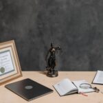 Biurko prawnika z statuą Temidy, laptopem i dokumentami