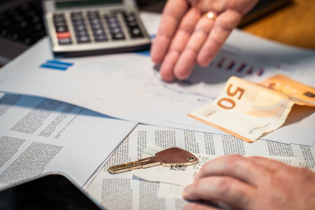 Dłonie przeglądające dokumenty finansowe, banknot 50 euro i klucz